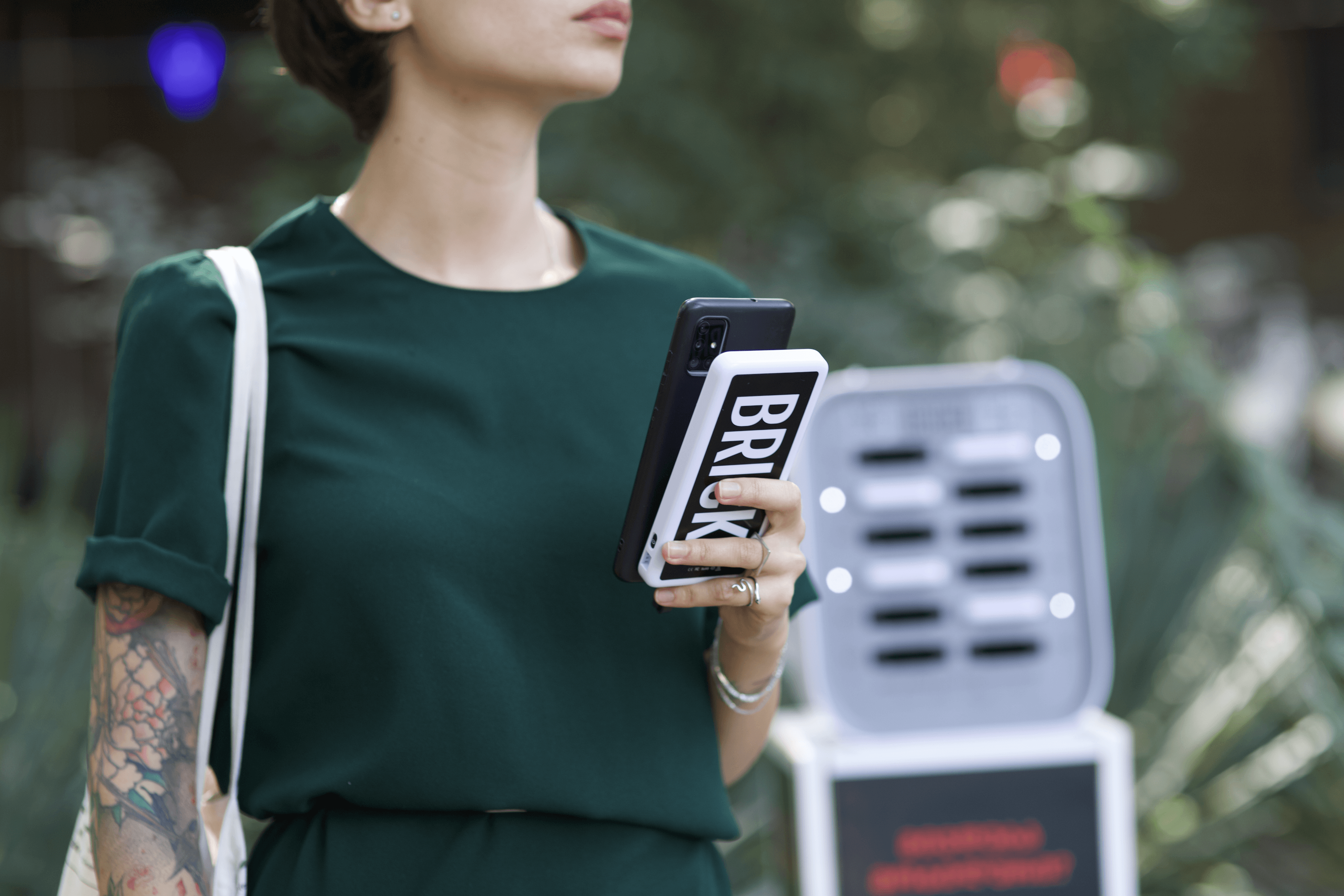 Eine Frau hält eine Brick-Powerbank vor einem Station