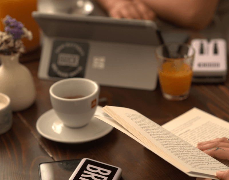 Mujer leyendo un libro mientras carga su teléfono con un Brick