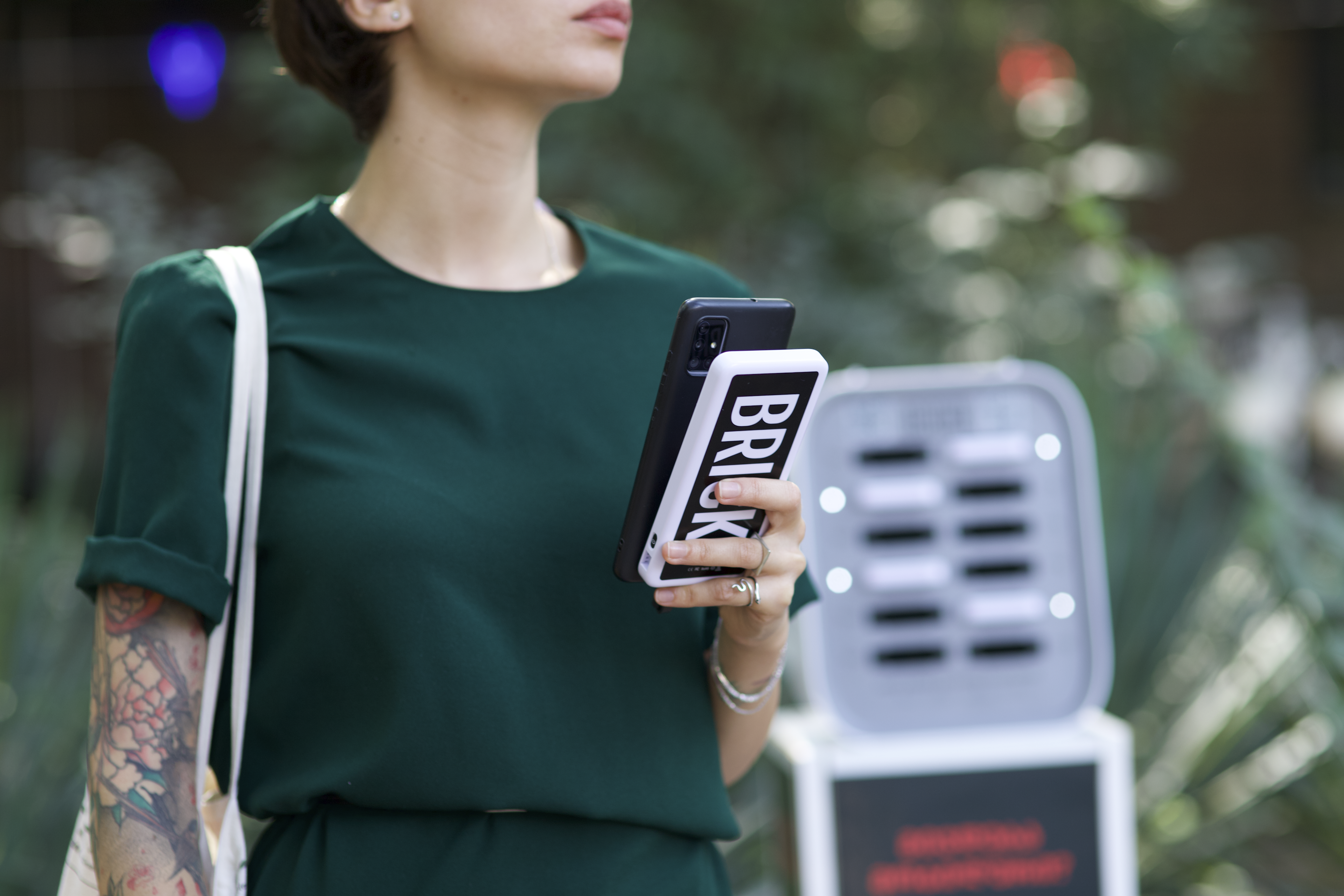 A woman holding a Brick power bank in front of a rental station